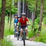 Mielno atrakcje - ścieżka rowerowa - 3 dzieci jedzie rowerami przez las
