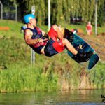 atrakcje Mielno - mężczyzna pływa na desce po jeziorze ciągnięty na linie